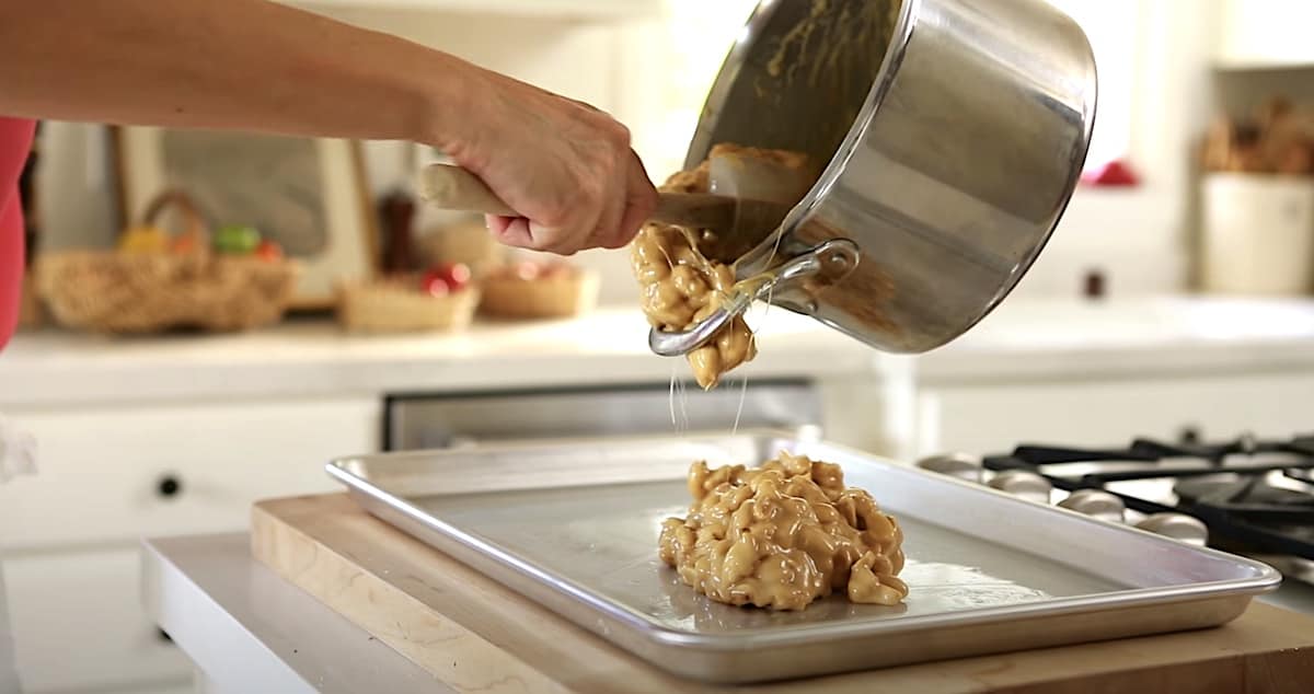 transferring sticky peanut brittle mixture from a pot to a greased baking sheet