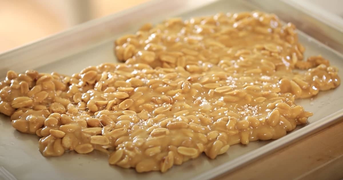 a mass of peanut brittle hardening on a sheet pan as it sets