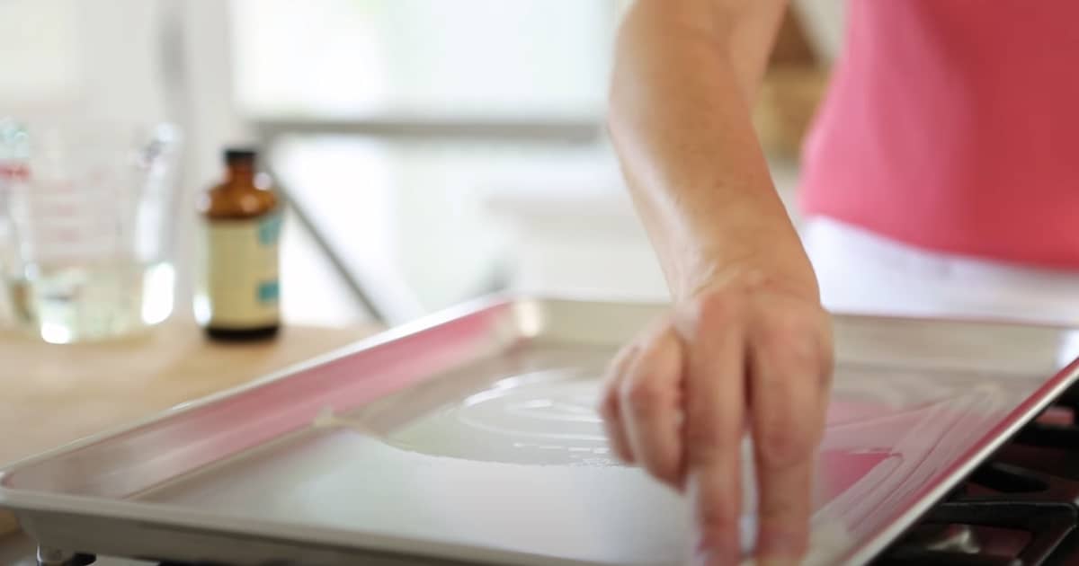 a person greasing a sheet pan with butter