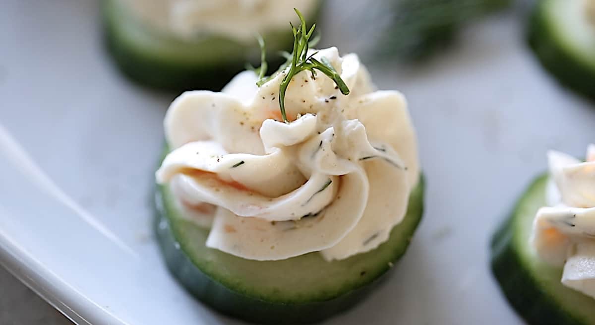 close up shot of salmon moussed pipped on to a cucumber slice