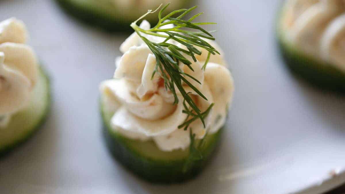 Close up of Salmon Mousse pipped on to a cucumber slice with fresh dill