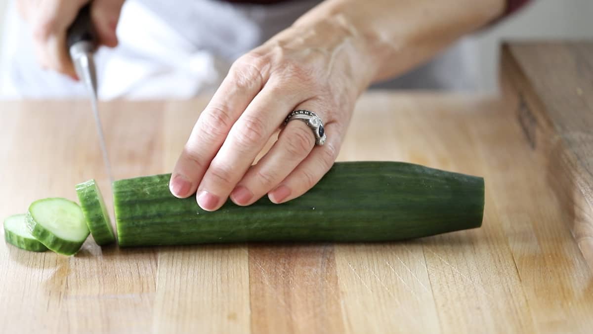 Slicing cucumber on a wooden cutting board