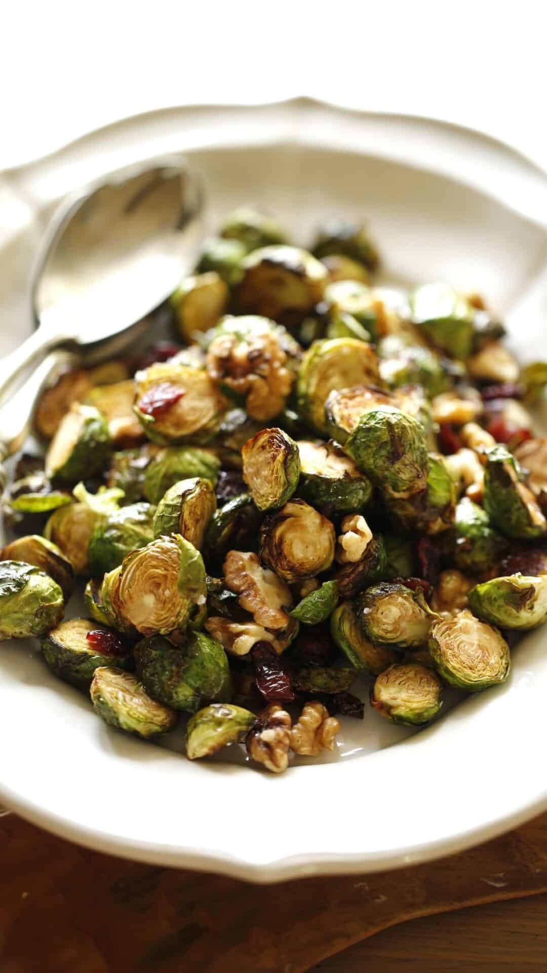 Brussel sprouts on a platter with a silver serving spoon