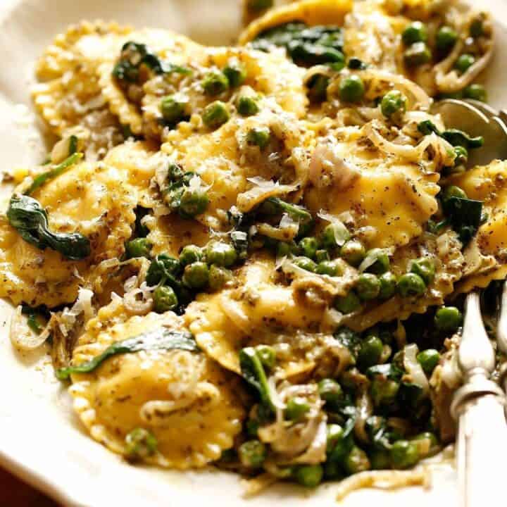 Ravioli with Creamy Pesto Sauce and Peas on a white platter