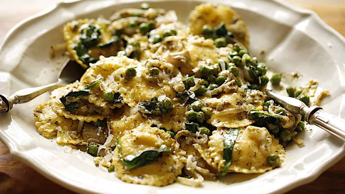 Ravioli with Pesto sauce and veggies on a white platter