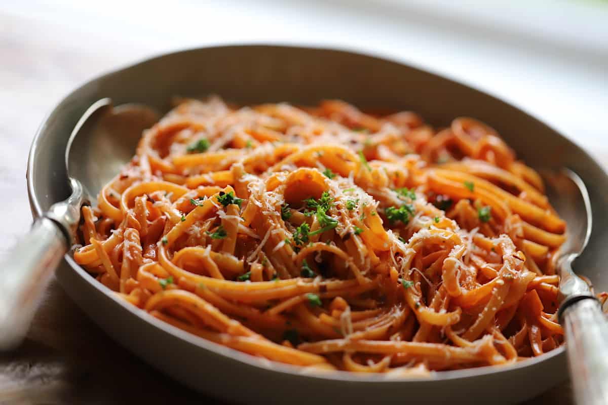 Creamy Tomato Saue Pasta in a gray serving bowl with silver serving poons