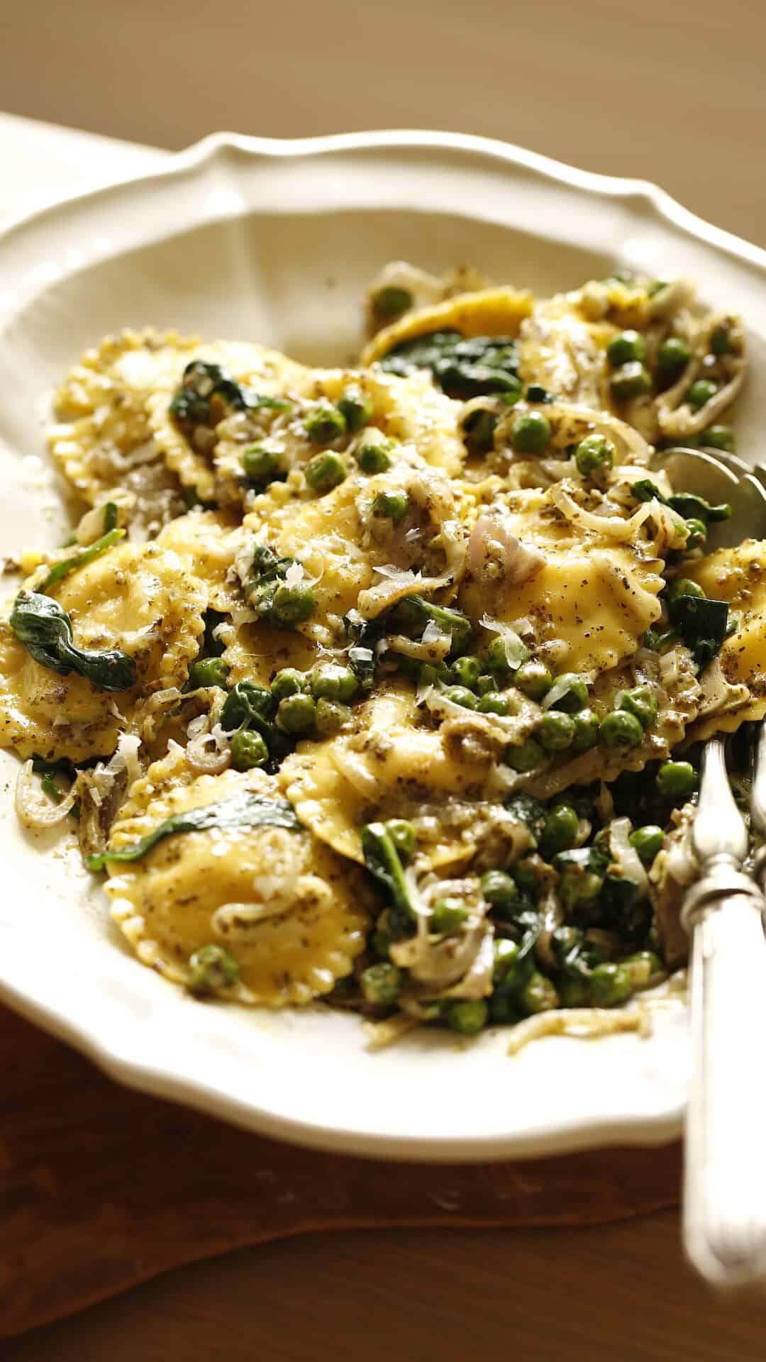 Ravioli with Creamy Pesto sauce and vegetables on a white platter