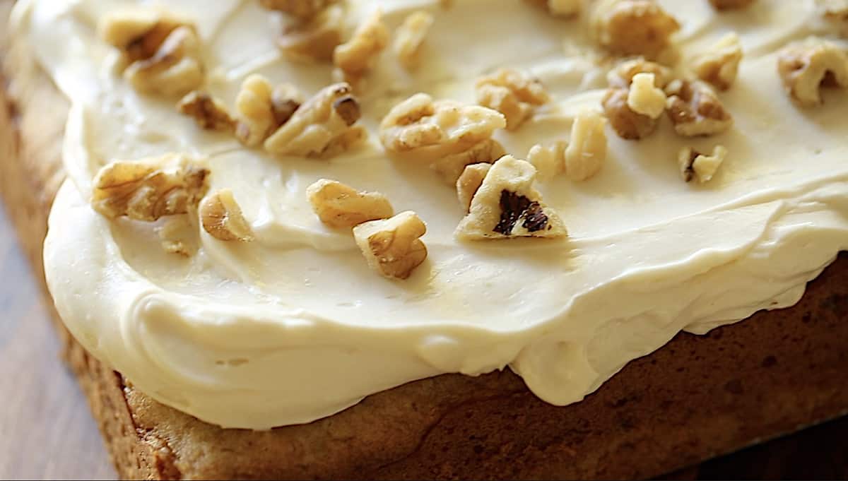 a detail of a cream cheese frosting whip on the corner of a cake.