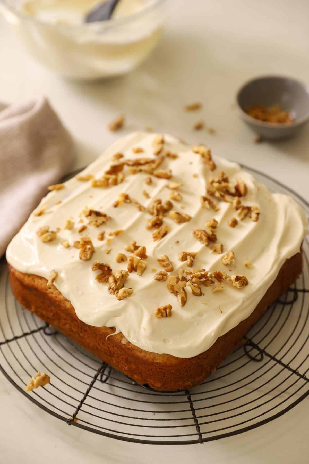 A frosted cake with walnuts on top.