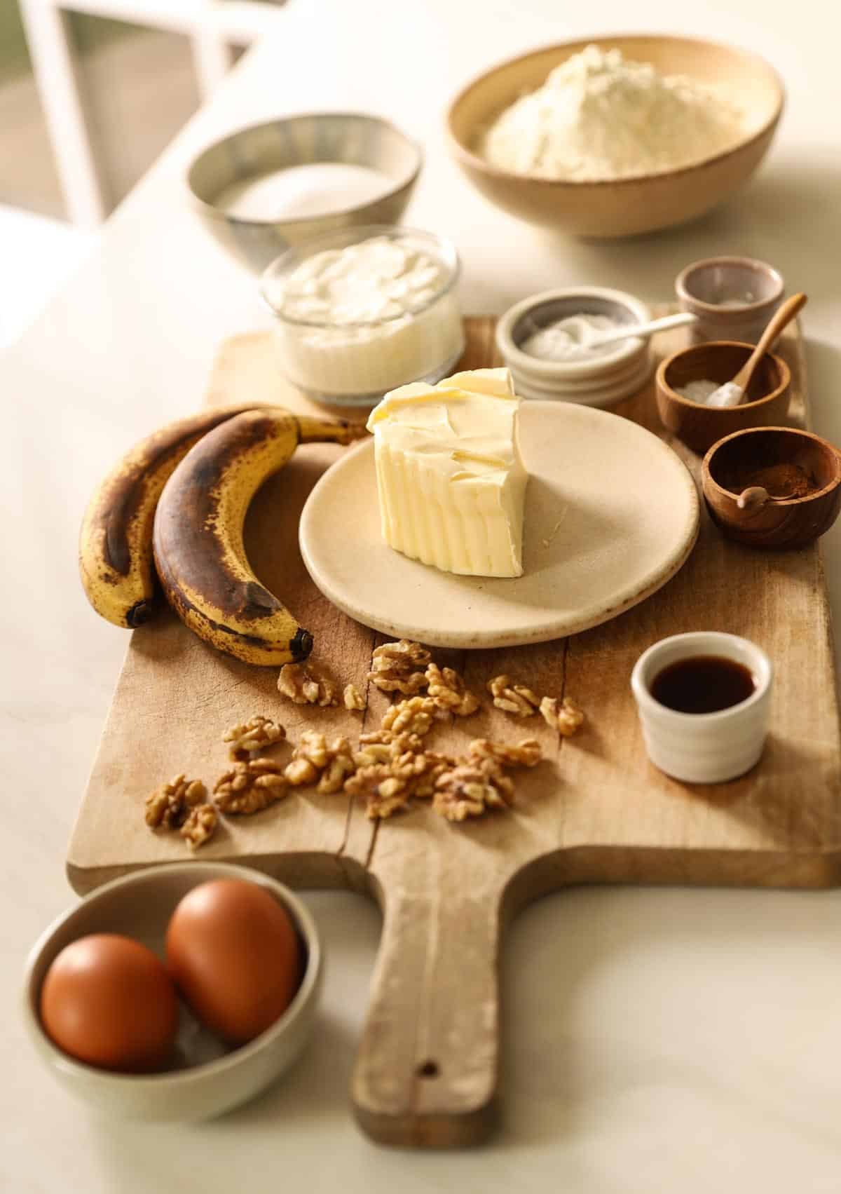 Ripe Bananas, Flour, sugar, butter eggs and other ingredients on a counter.