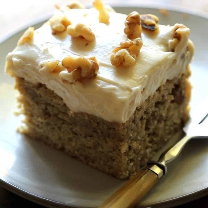 a slice of banana cake with cream cheese frosting on a plate