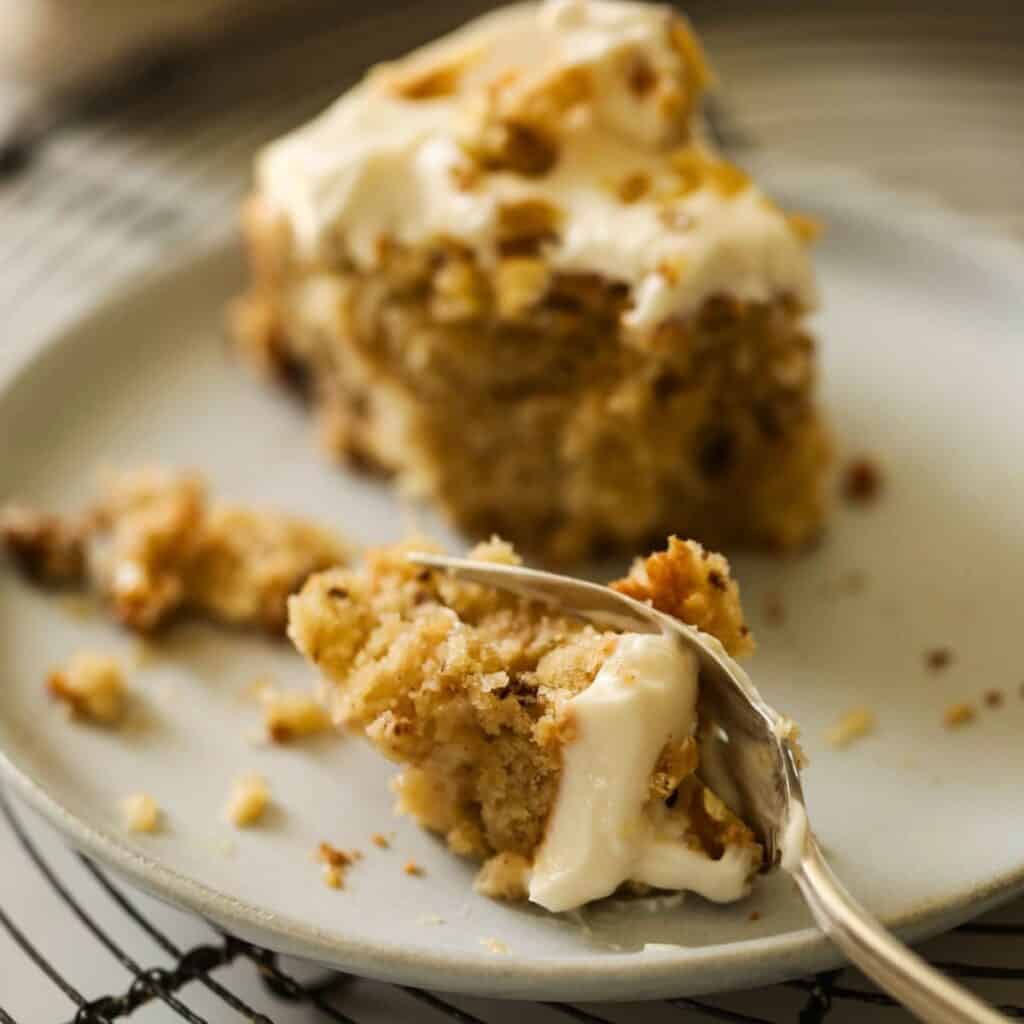 A fork taking a bite of cake on a plate.