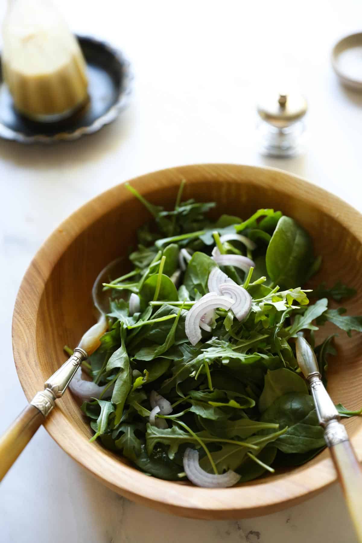 A tossed green sald in a wooden bowl with French vinaigrette