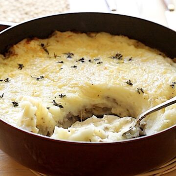 Hachis Parmentier in a red casserole dish with a serving taken out of it