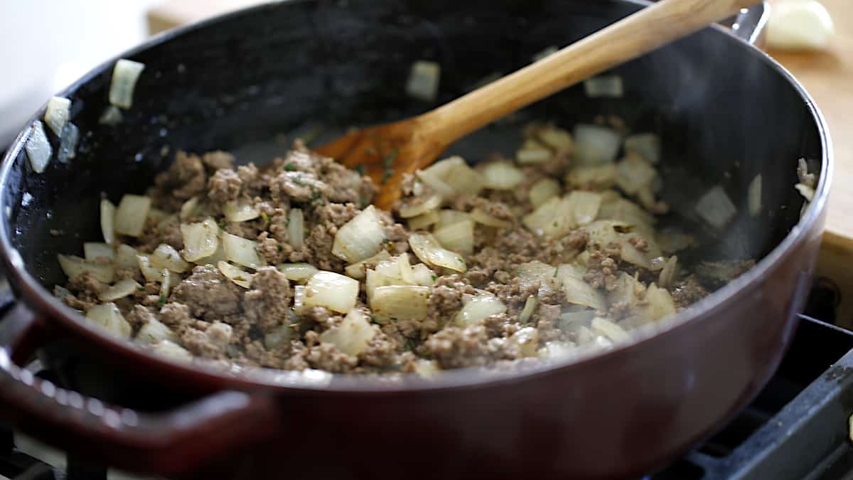 a large casserole simmering ground beef, onions and spices
