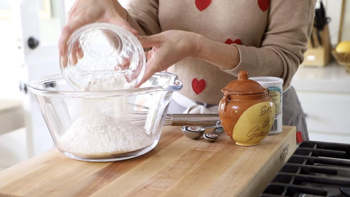 A person adding flour to a bowl