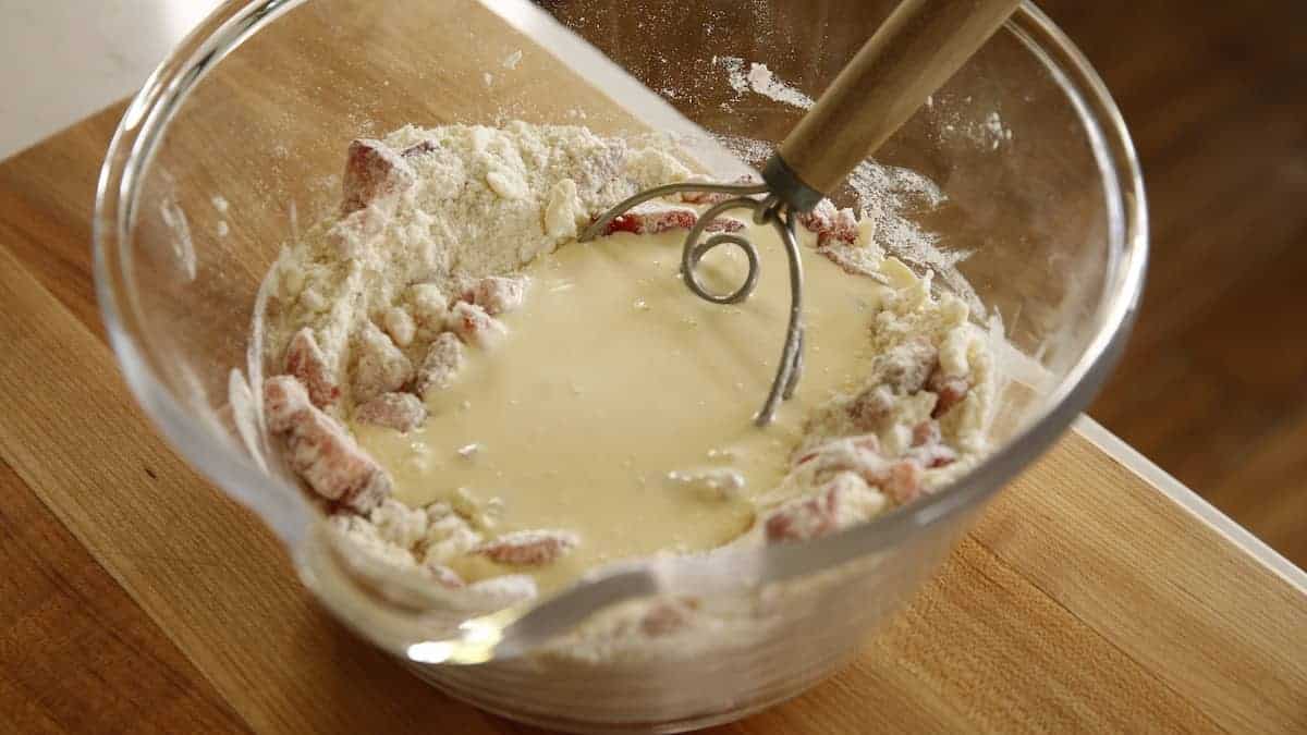 a bowl holding a mixture of scone dry ingredients with a well in the center filled with heavy cream mixture