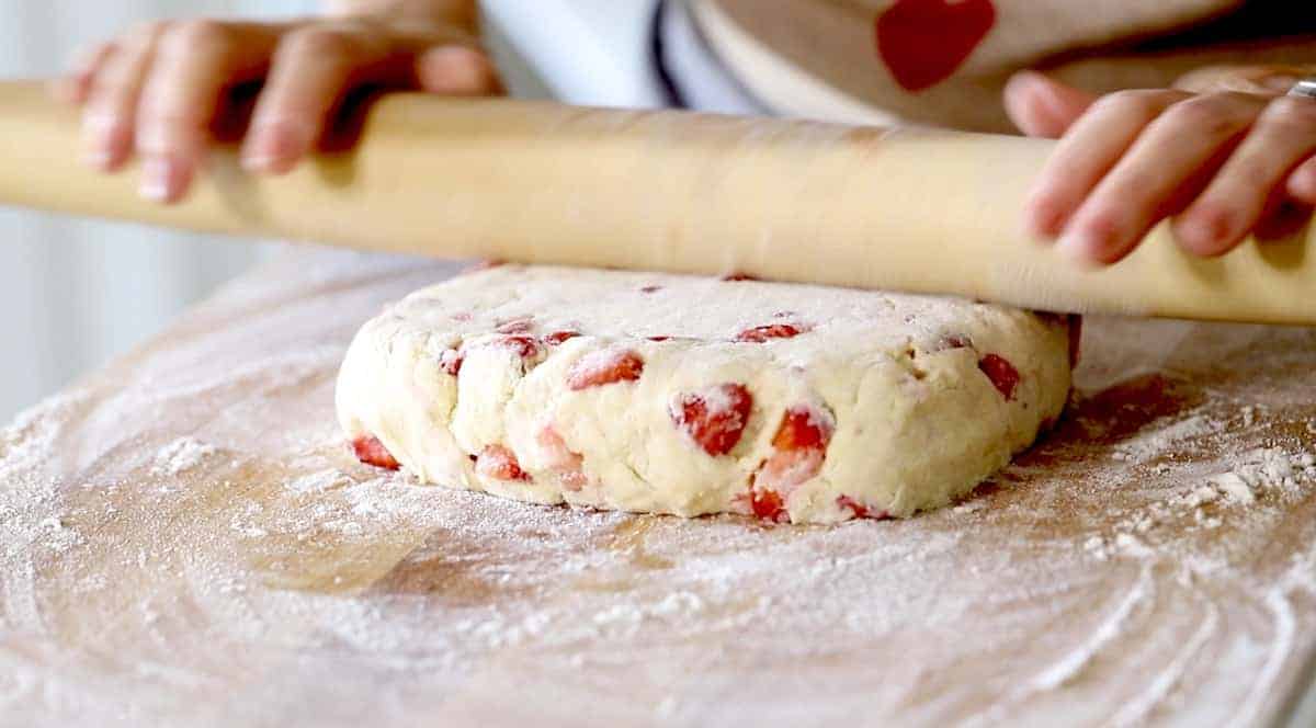 a person rolling scone dough into a square