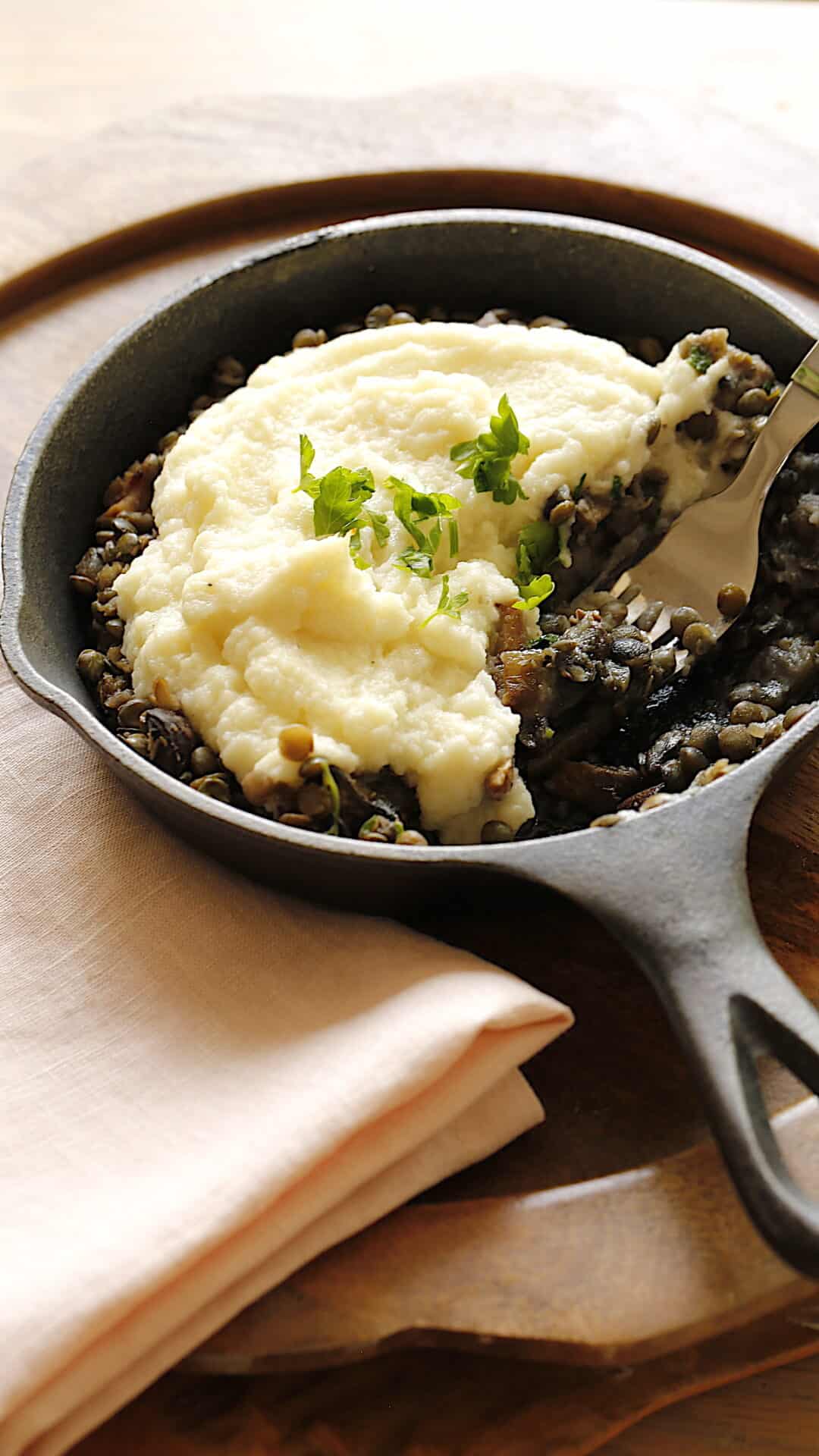 a skillet filled with mushrooms and lentil mixture topped with cauliflower mash