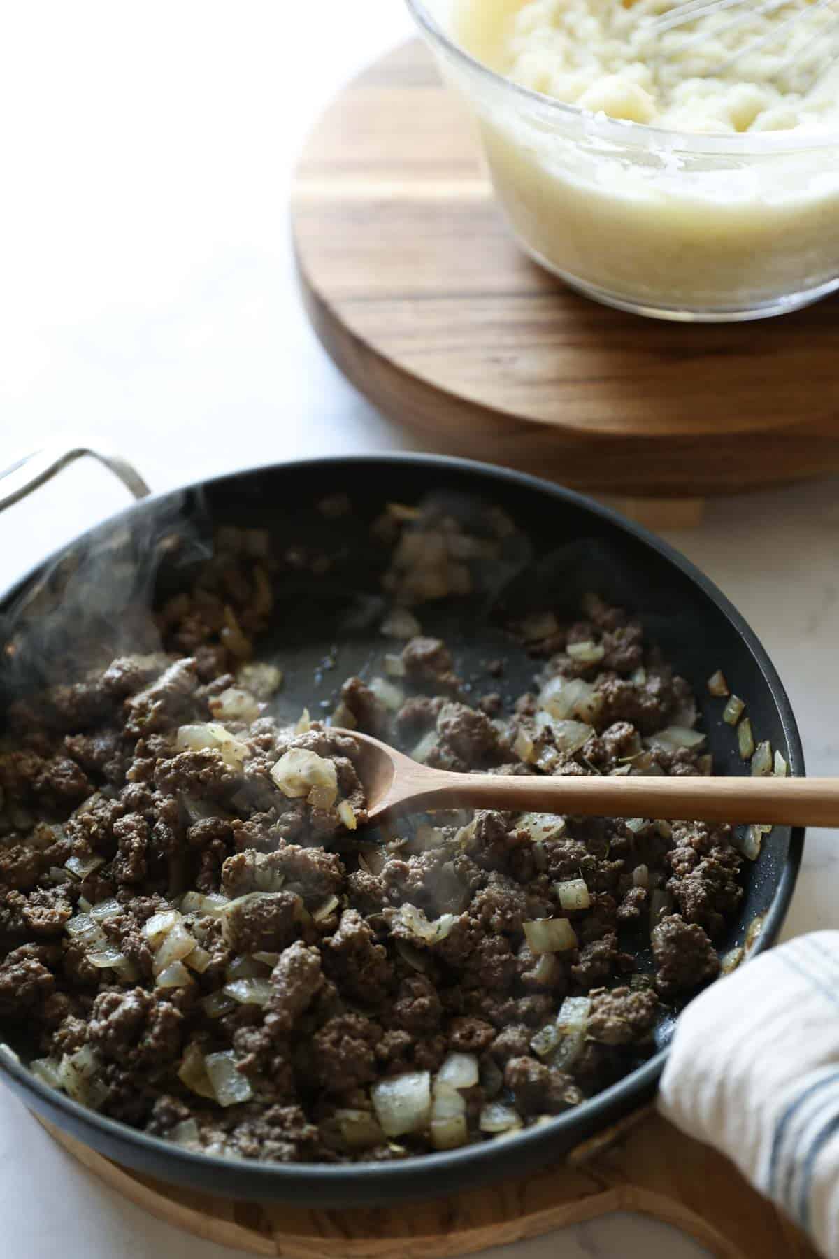 ground beef and onions simmering in a skillet