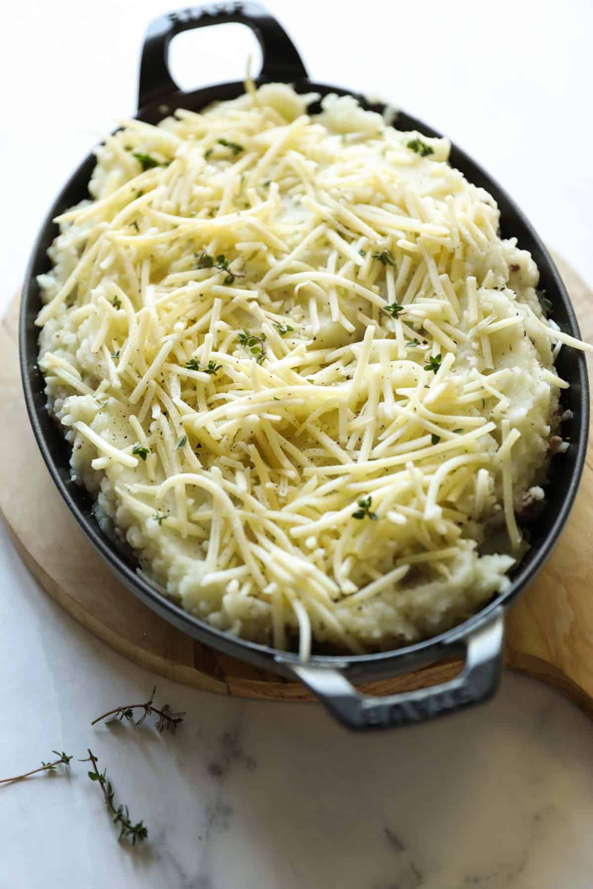 a casserole dish with mashed potatoes and shredded cheese on top