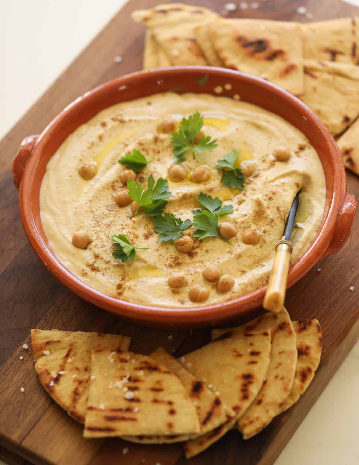 grilled pita and creamy hummus in a terra cotta dish