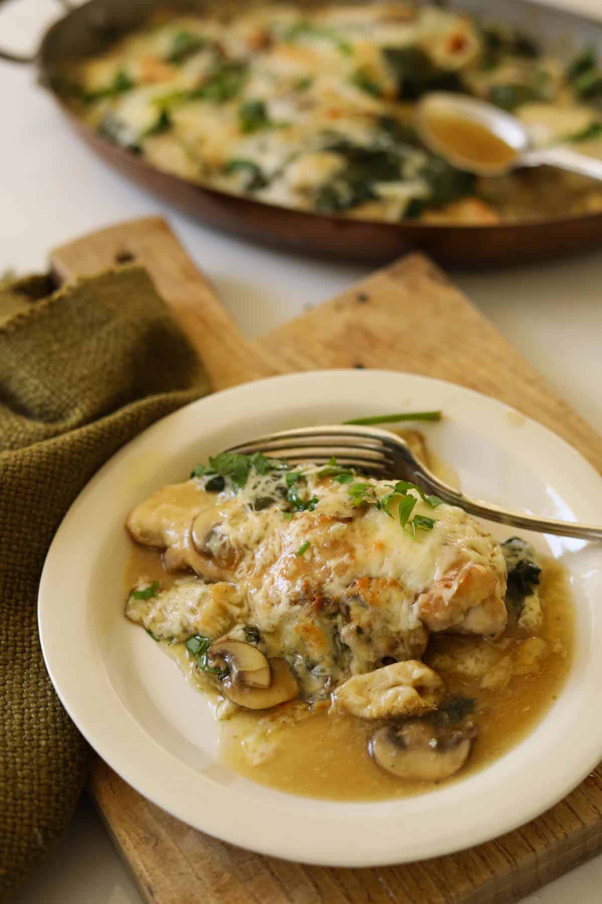 A serving of chicken with artichokes, spinach and melted cheese.