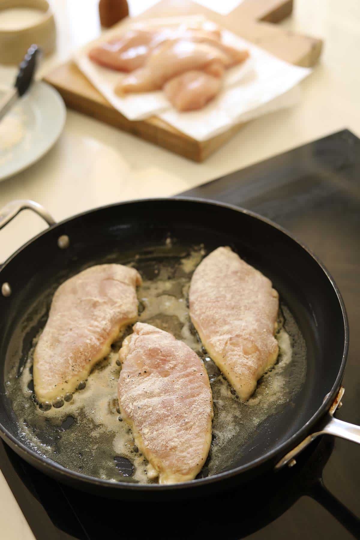 chicken breasts searing in a pan.