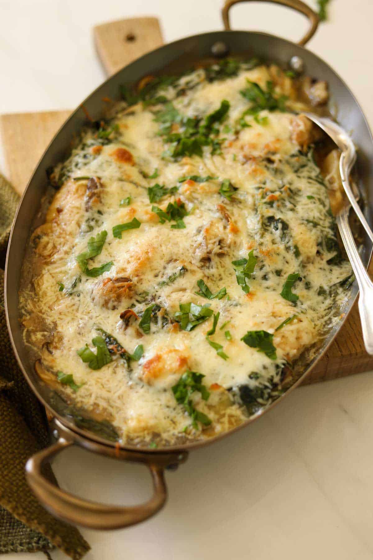 A copper gratin pan filled with an artichoke chickem bake