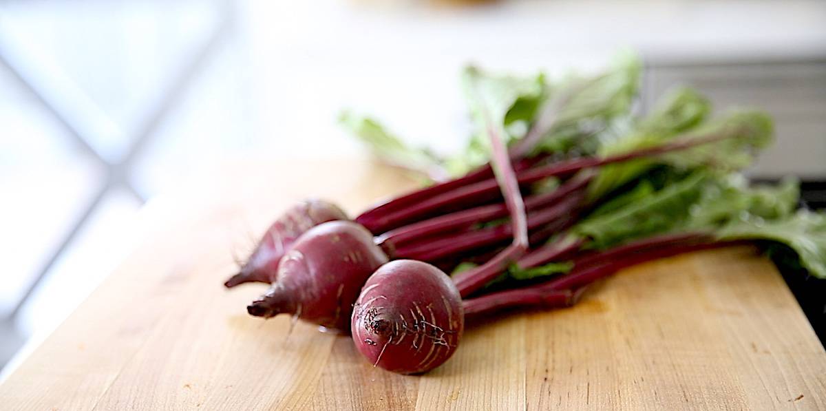 Fresh beets with their greens attached on a cutting board