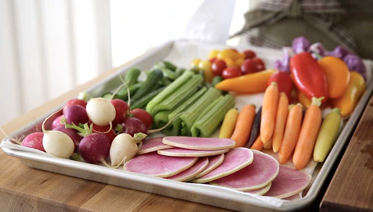 A sheet tray lined with a damp kitchen towel loaded up with colorful vegetables