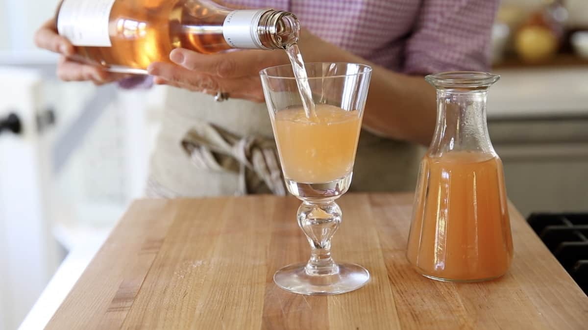 a person filling a glass with rose wine