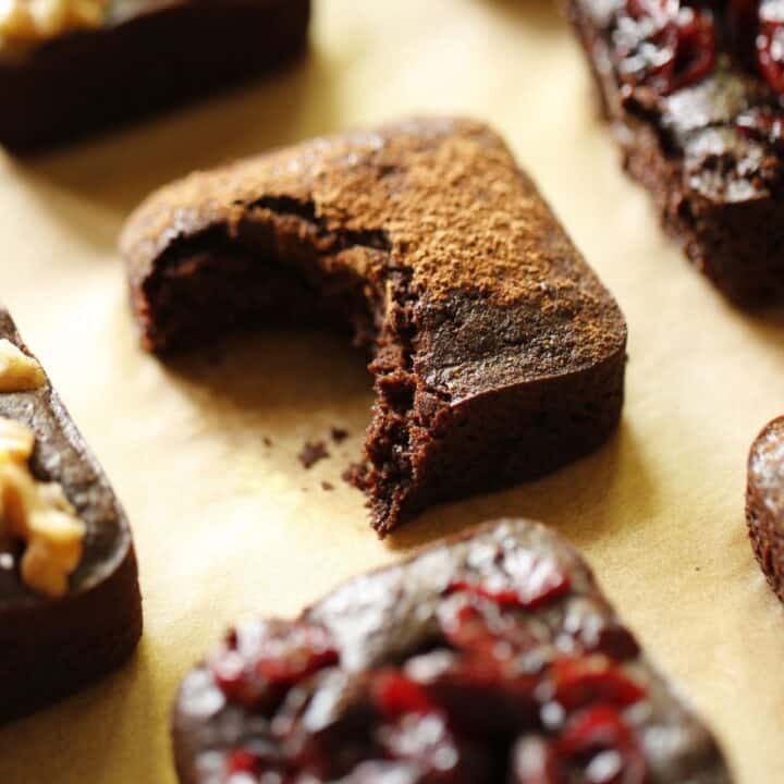 a selection of vegan brownies on parchment paper with one with a bite taken out