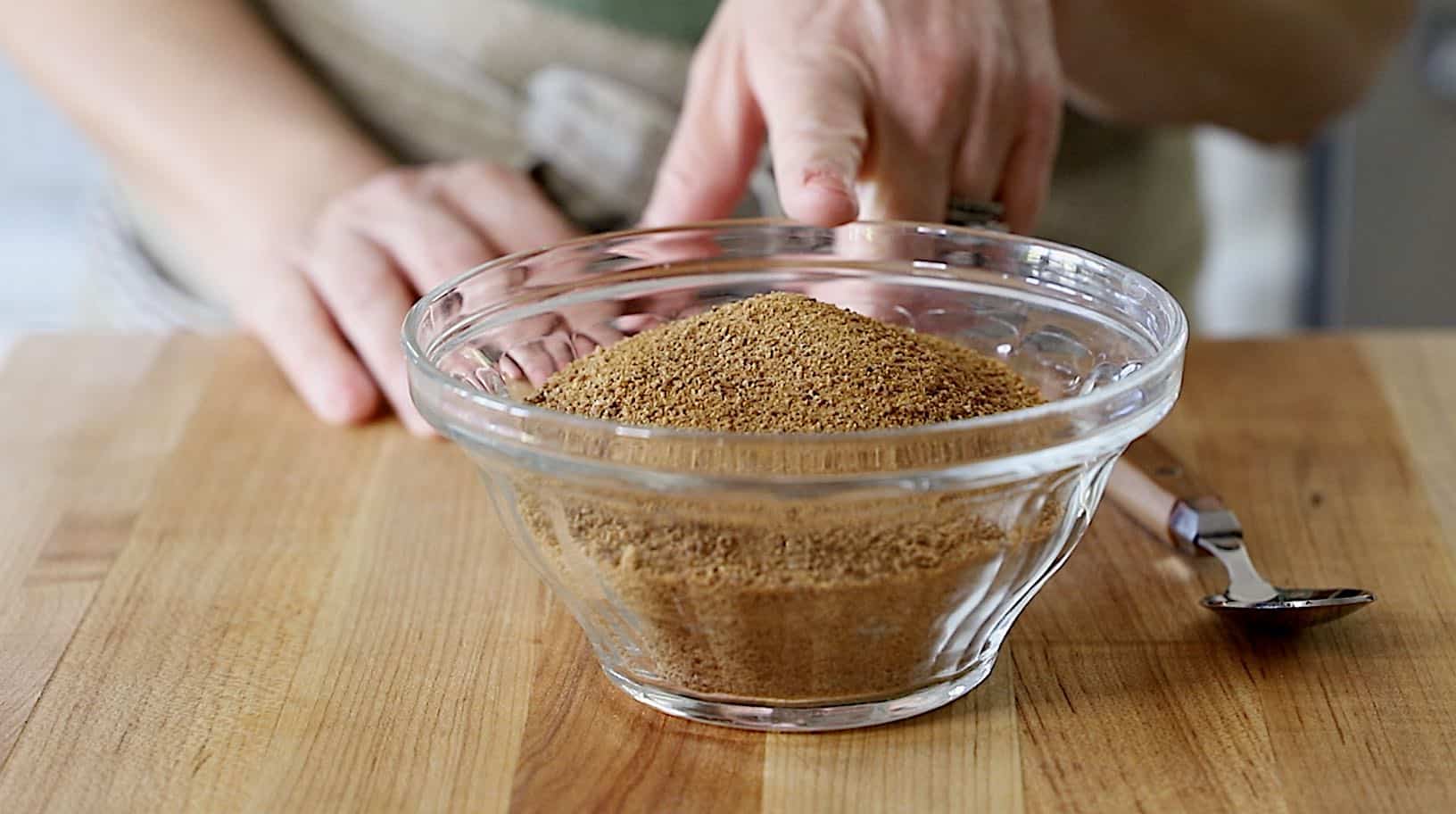 a person pointing to a bowl of brown coconut sugar