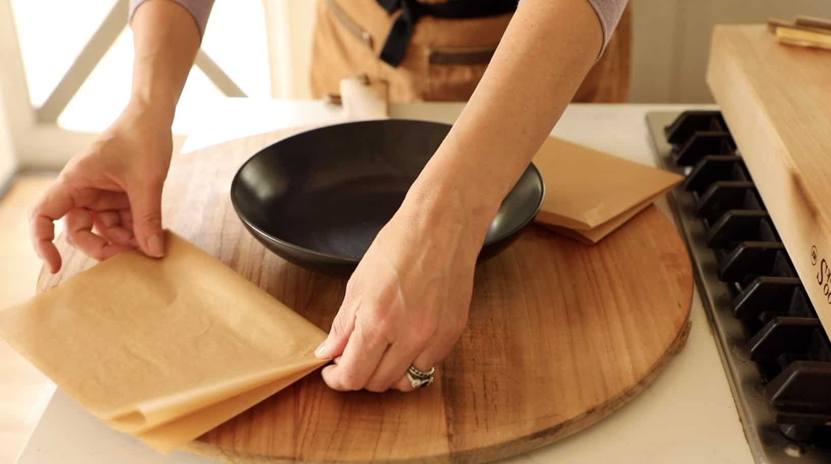 A person placing parchment paper sheets on a board