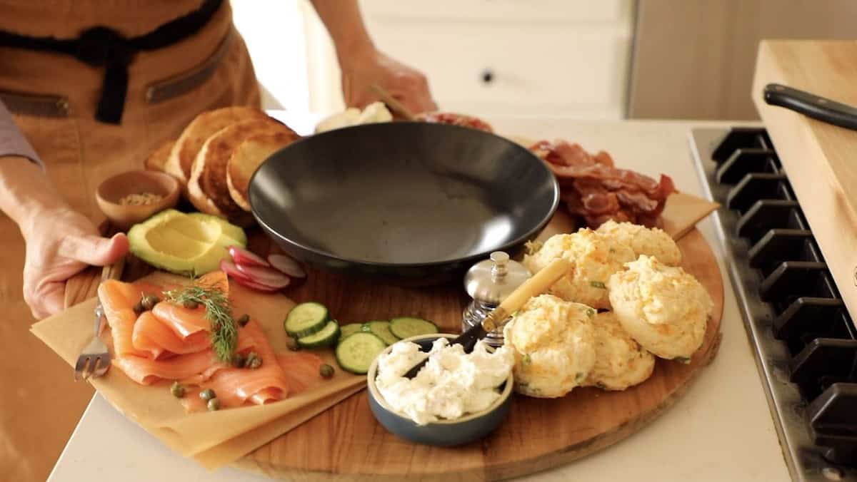 a person taking a board away that is loaded with breakfast foods