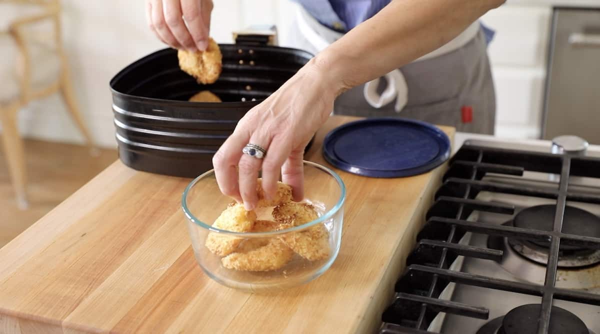 a person placing air fried shrimp in a container for storage