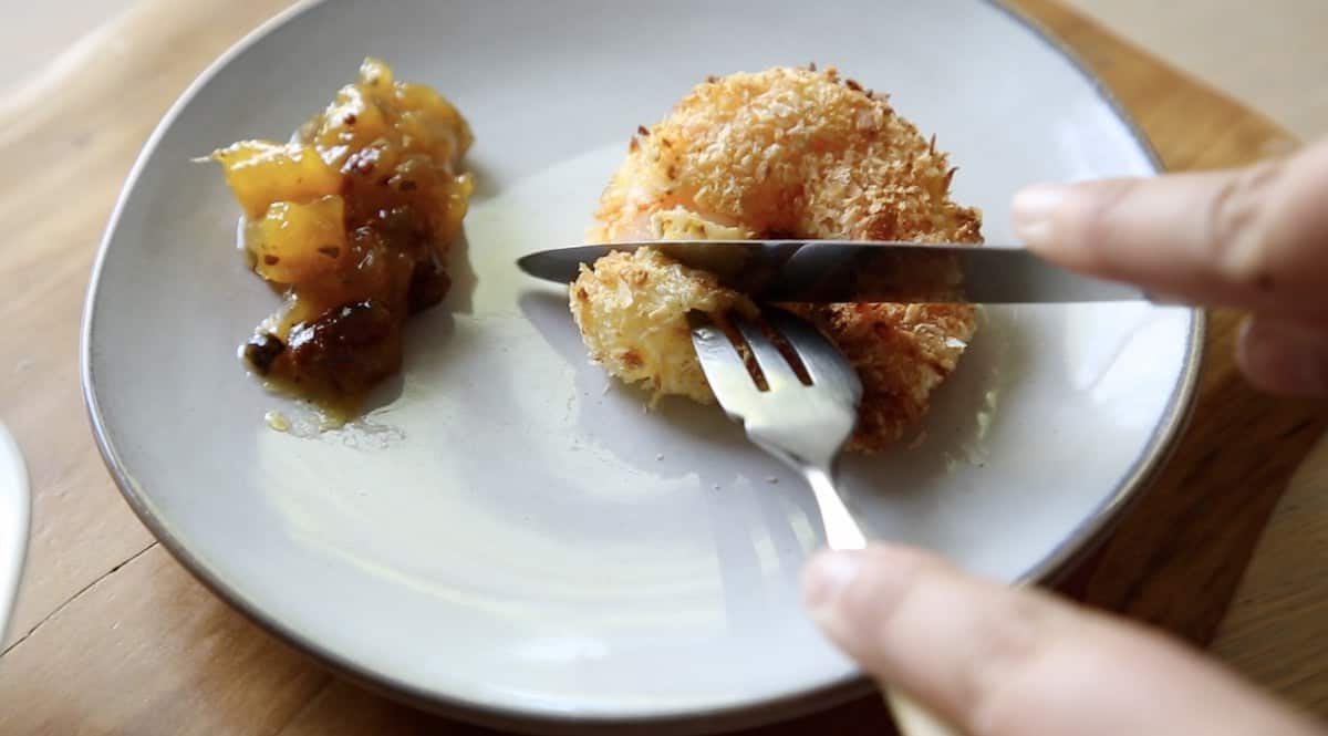 a person cutting into an air fried coconut shrimp on a plate with a fork