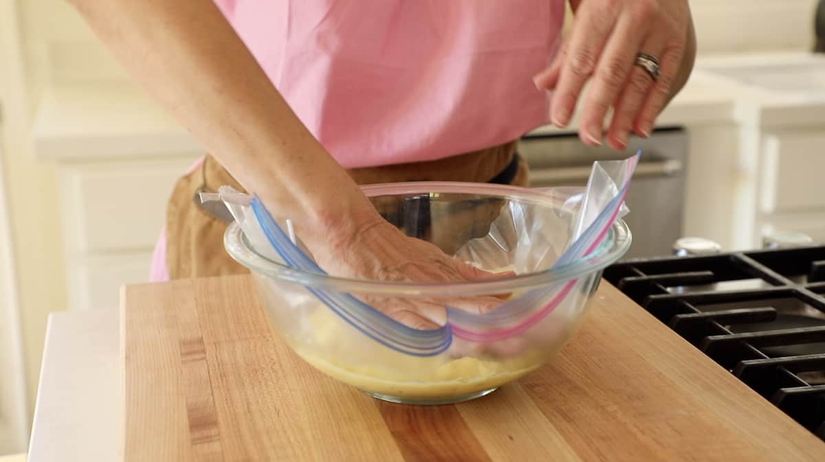 Placing plastic wrap over a bowl of pastry cream