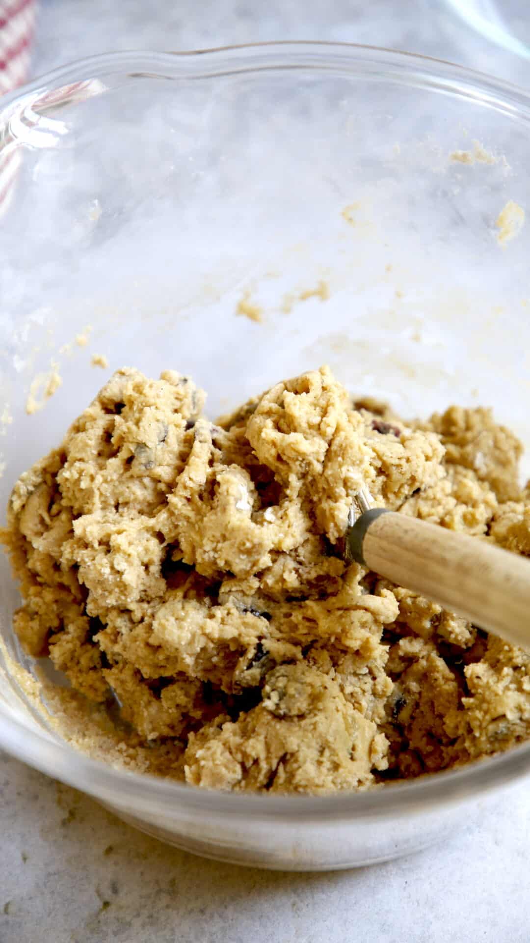 Cookie dough formed in a glass bowl with a danish dough whisk in it