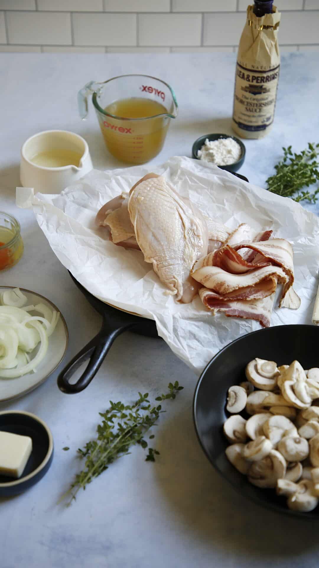 Ingredients laid out on a counter such as chicken, bacon, onions and mushrooms