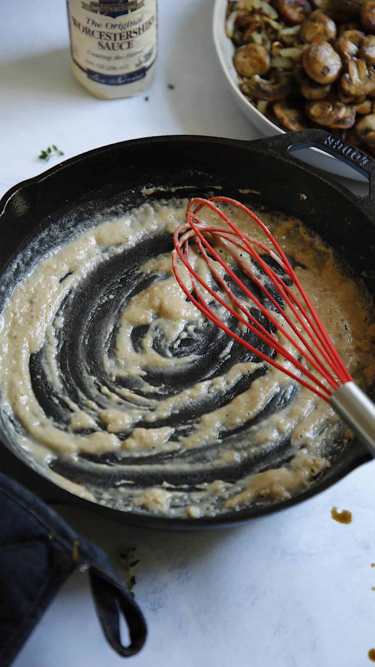a cast iron skillet with a whisk stiring a roux made with butter and flour