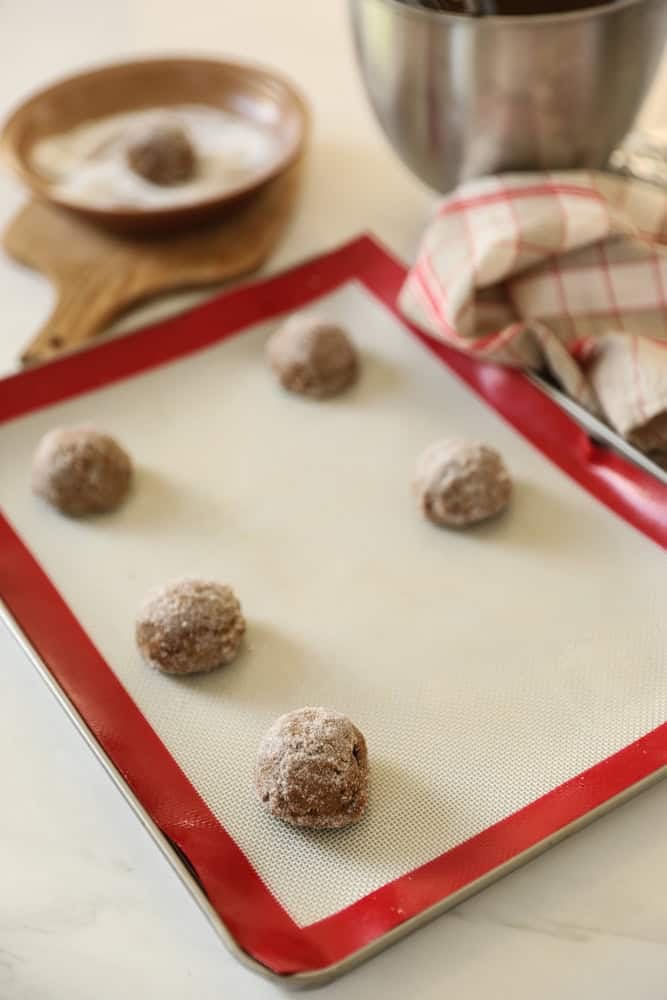 cookie balls rolled in sugar and placed on a baking tray.