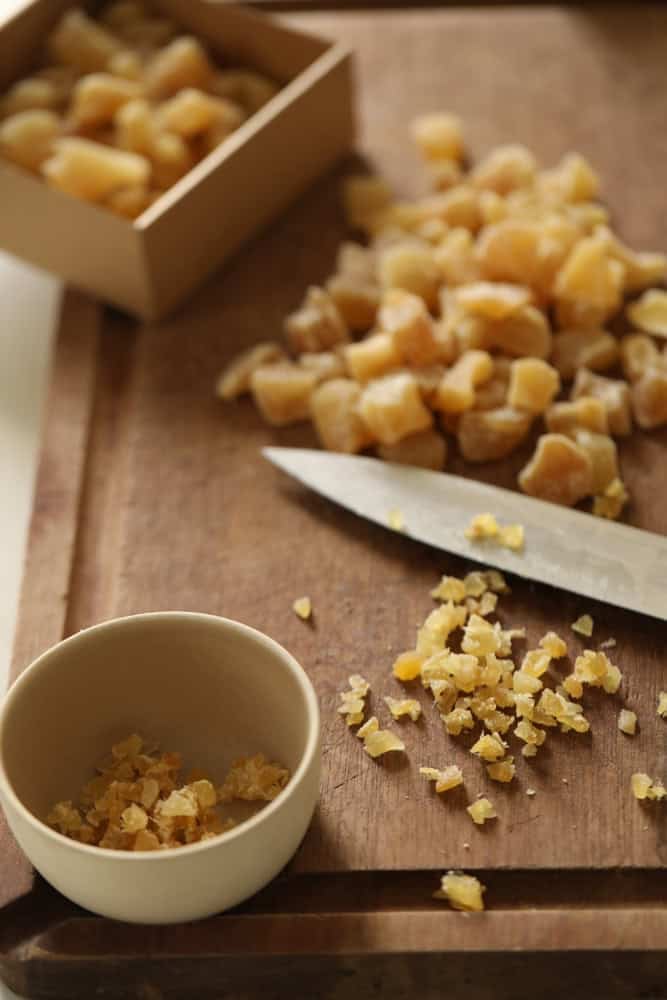 candied ginger on a cutting board being diced into small pieces.