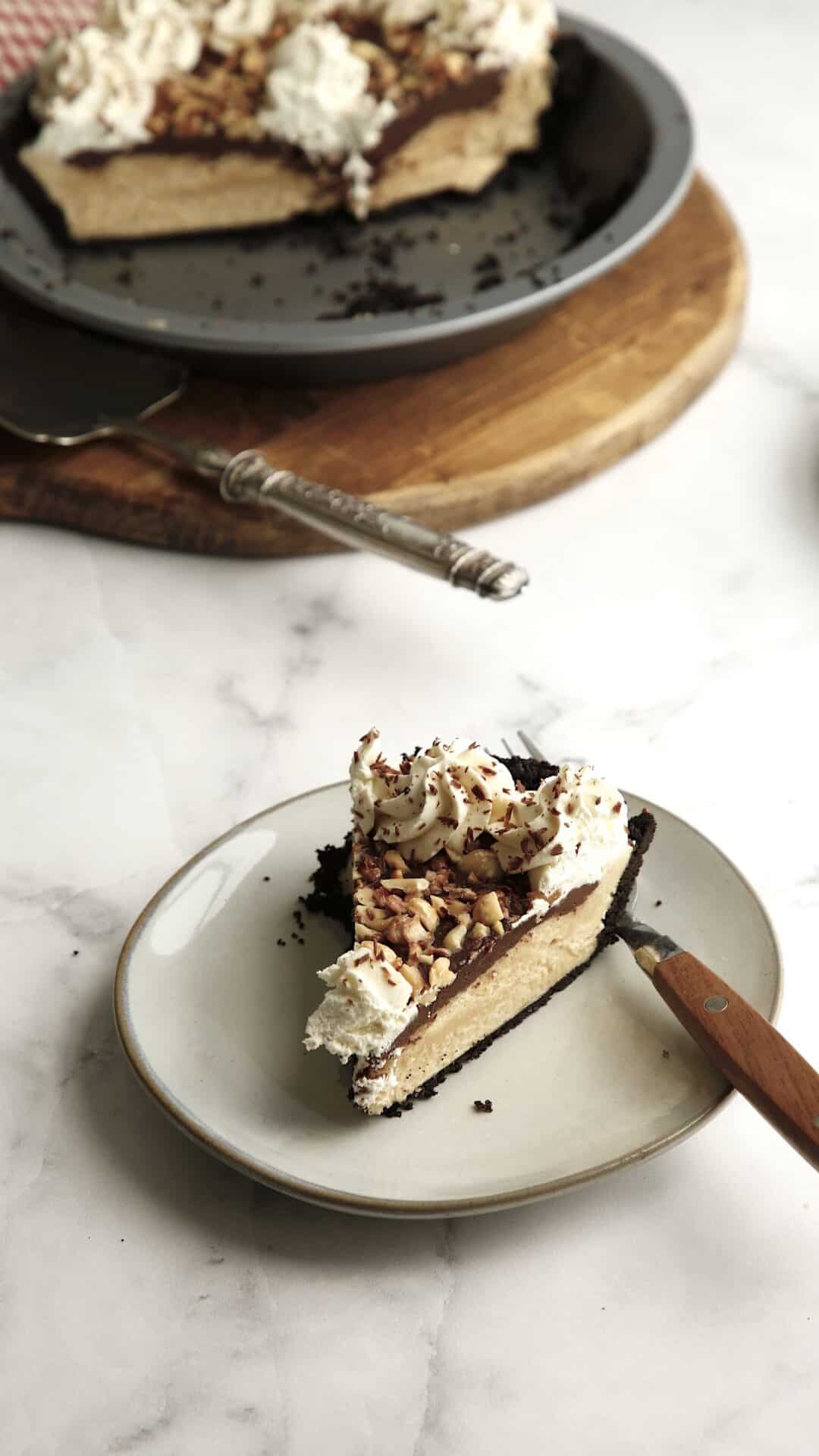 a slice of pie on a plate with the whole pie in the background