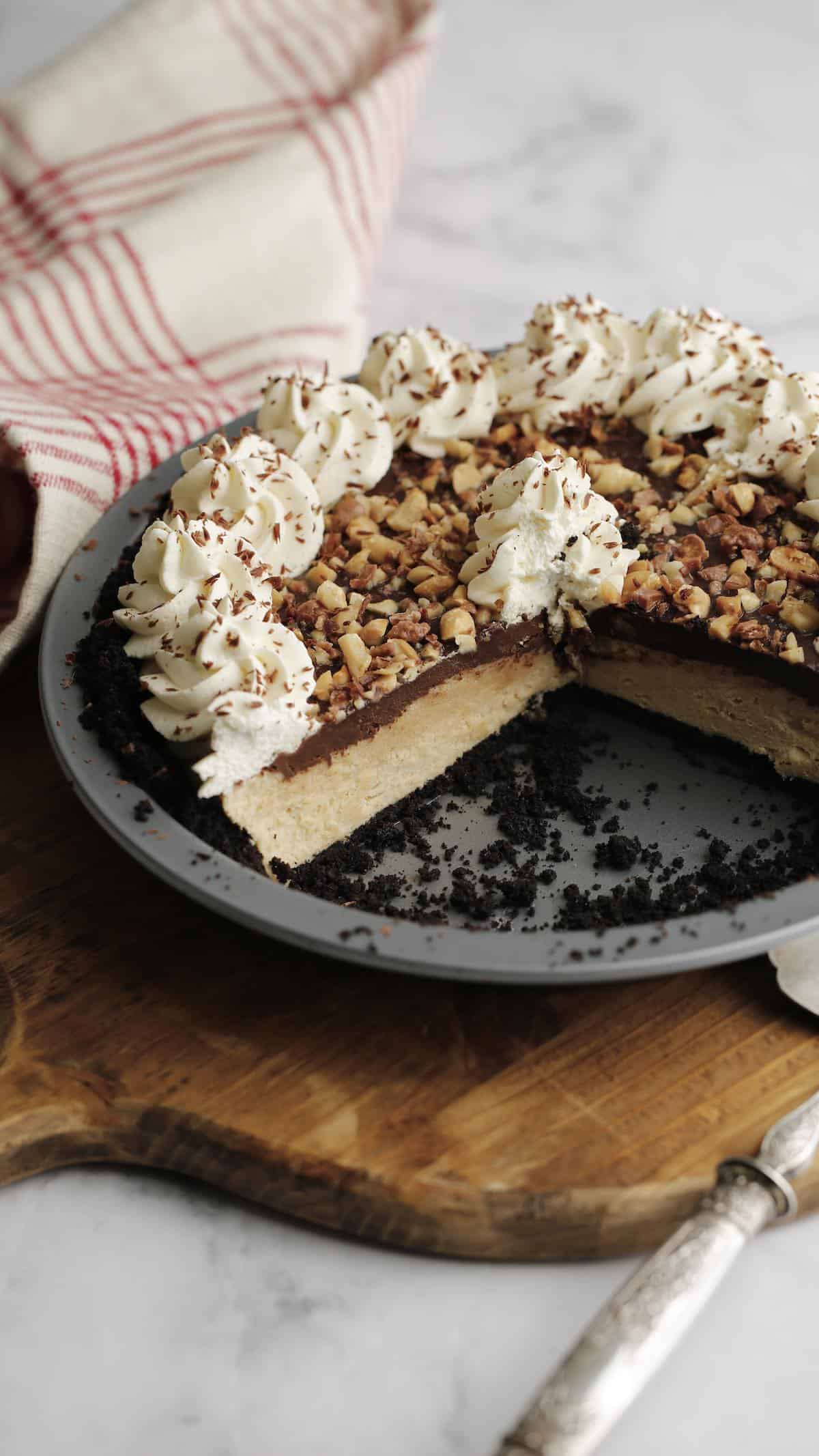 a peanut butter pie with chocolate ganache in a metal tin with slices taken out