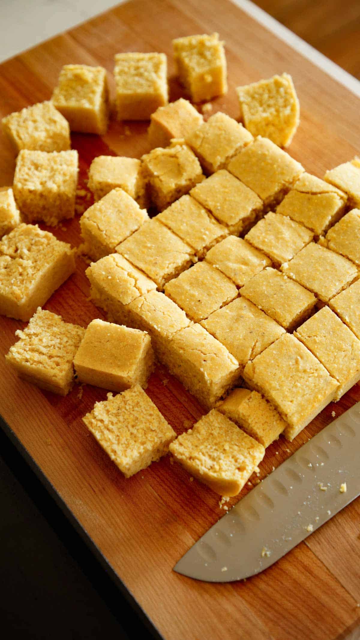 Freshly baked cornbread on a cutting board sliced into small cubes