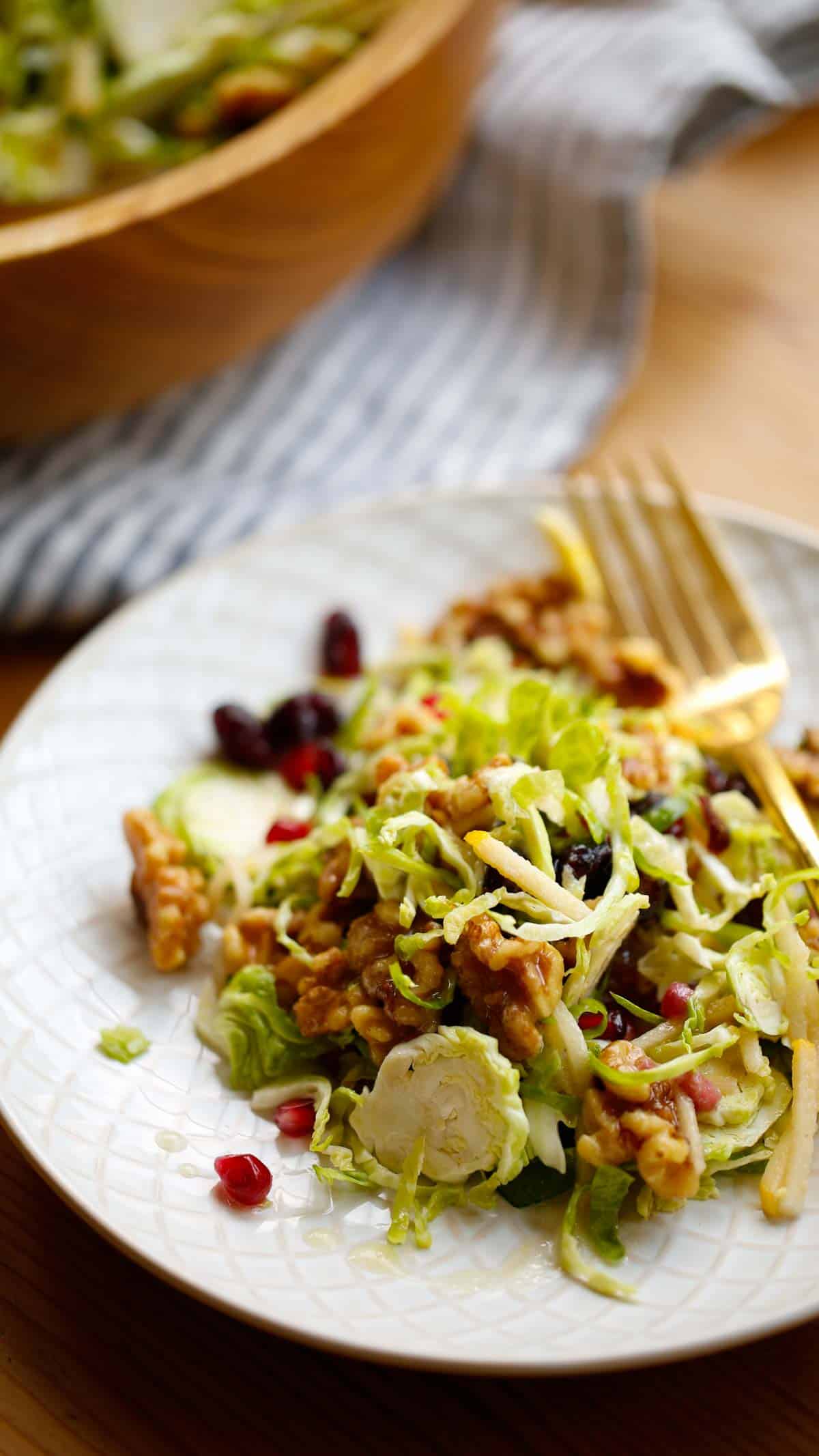 A serving of salad on a plate with salad bowl in background