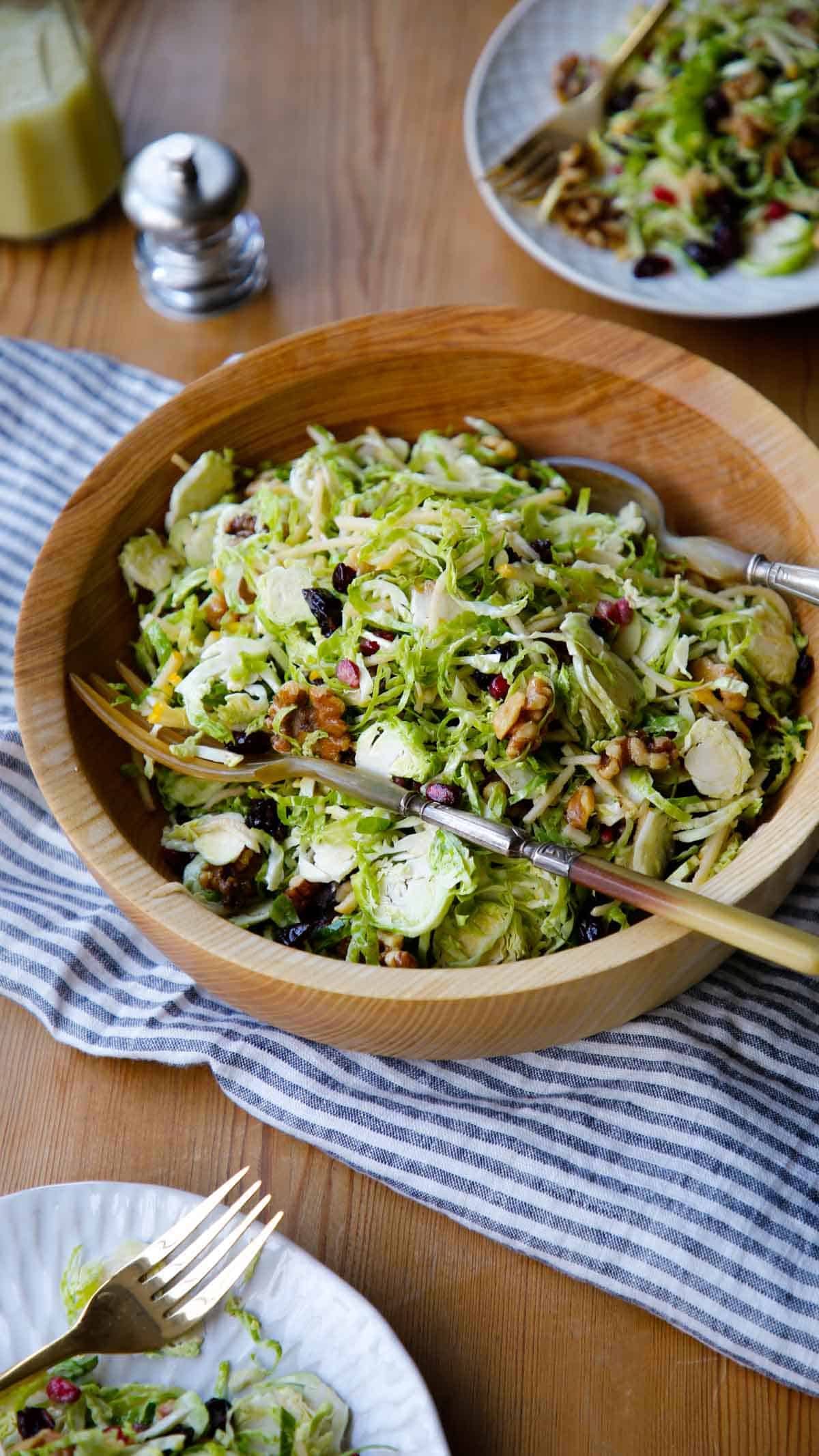 Overhead shot of salad bowl filled with salad and 2 servings on plates with forks