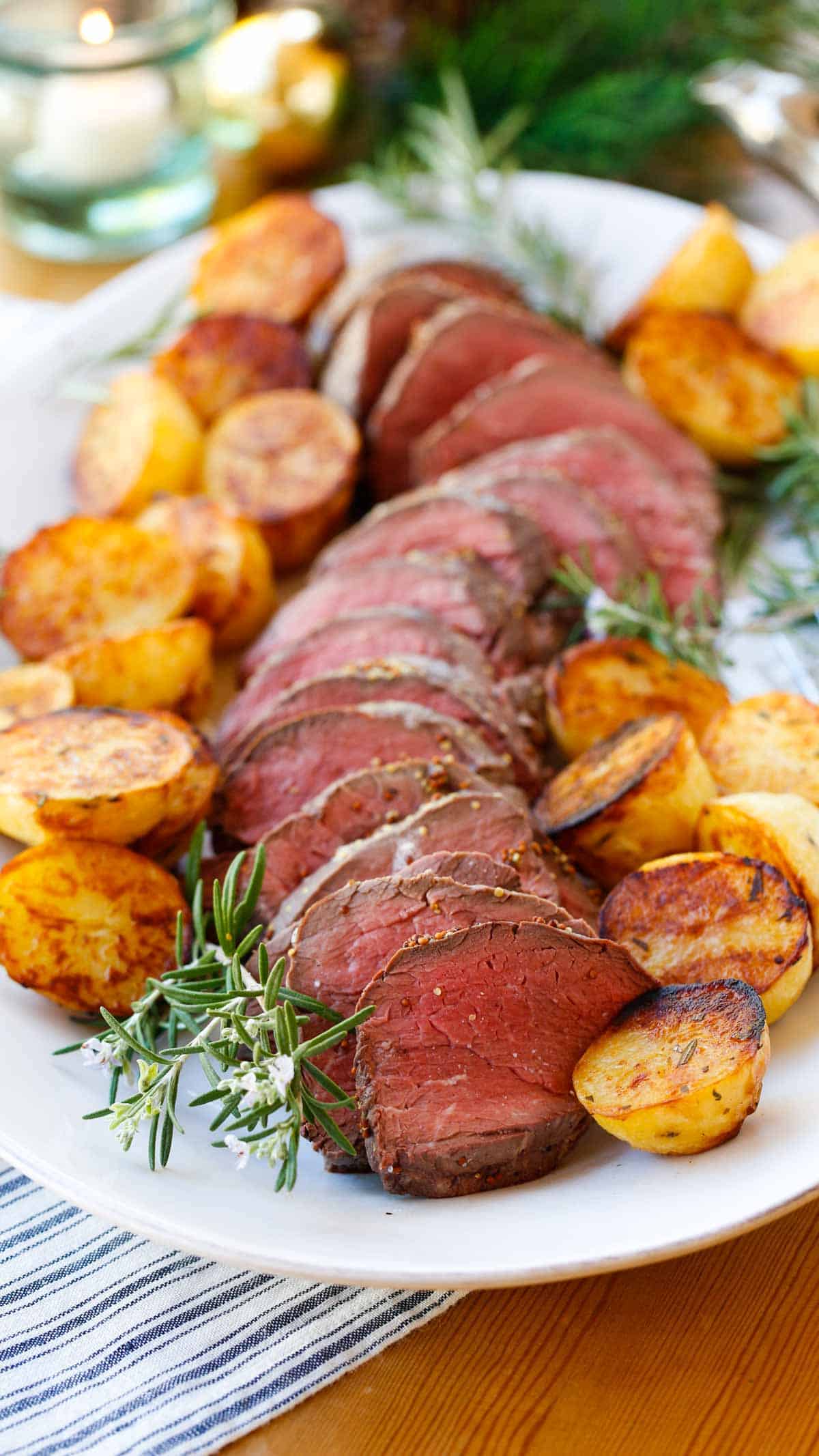 a platter of filet of beef tenderloin with Yukon Gold Potatoes garnished with Rosemary